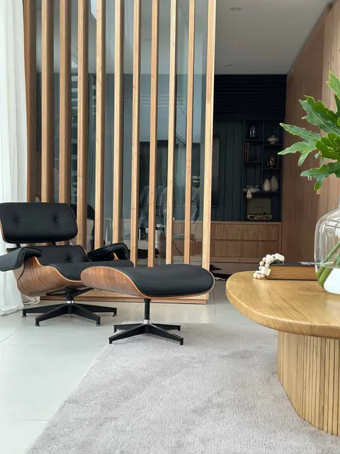Living con sillón de cuero negro, madera natural y una mesa con objetos de diseño.