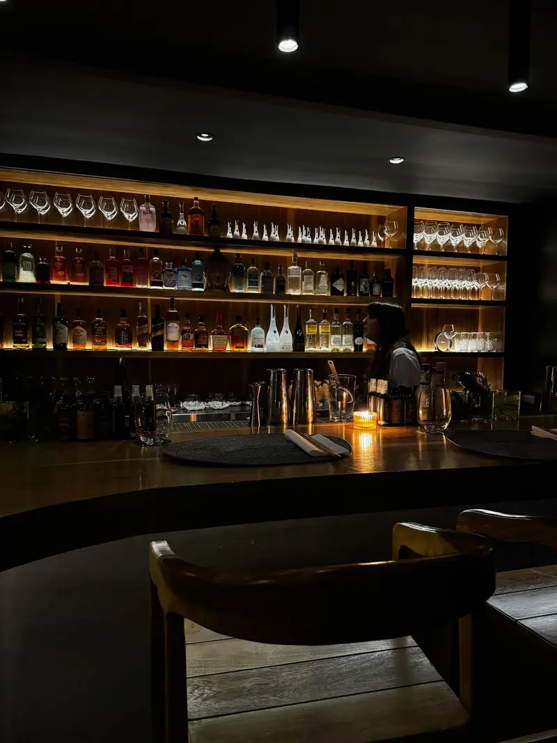 Barra de PAUKA con estantes de botellas iluminados y banquetas altas.
